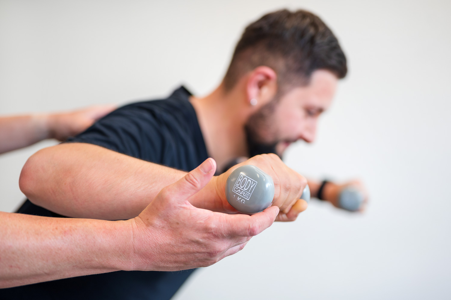 A patient trains his back stability with two small dumbbells.