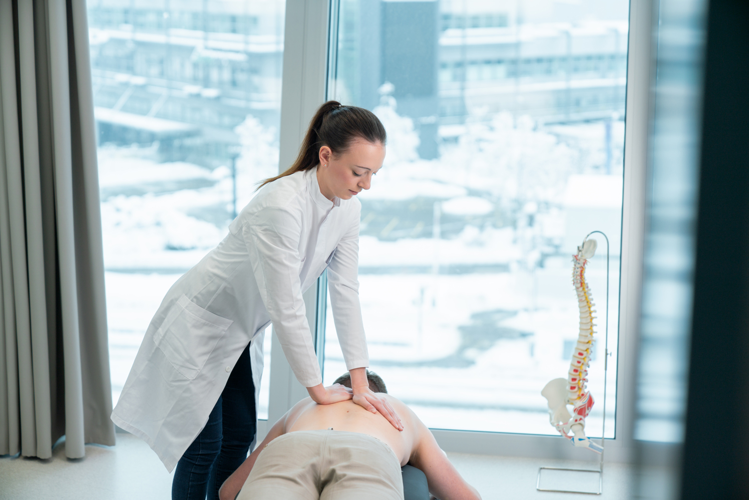 A chiropractor examines the back of a patient